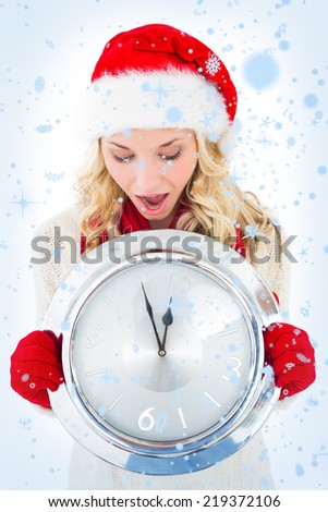 Festive blonde holding large clock against snow falling