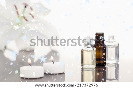 Composite image of snow falling against white orchid with lighted white candles and small phials