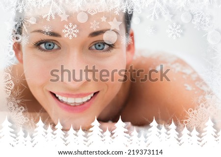 Peaceful brunette lying with salt scrub on back smiling at camera against fir tree forest and snowflakes
