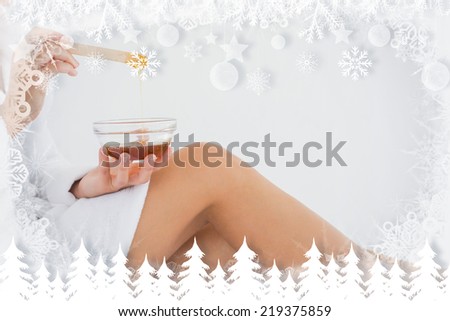 Side view of woman holding hot wax in bowl at spa center against fir tree forest and snowflakes