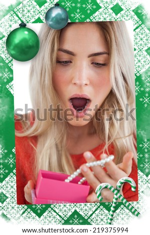 Shocked woman discovering necklace in a gift box against christmas frame