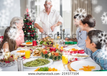 Extended family at dining table for christmas dinner in house against snowflakes