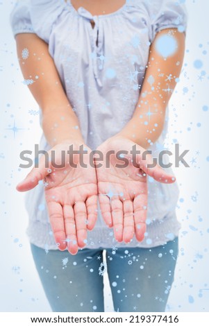 Casual young woman holding hands out against snow falling