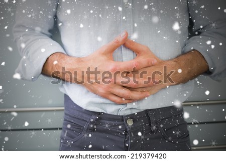 Mid section of a man suffering from stomach pain against snow falling