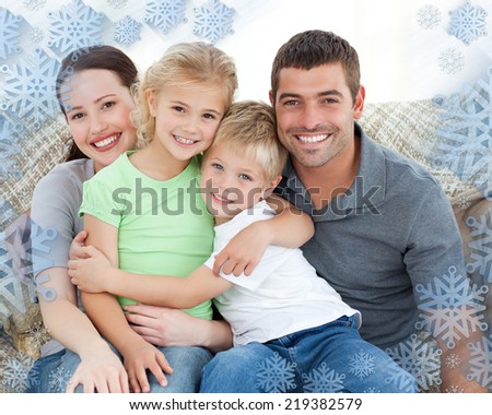 Adorable family sitting on the sofa and smiling against snowflake frame