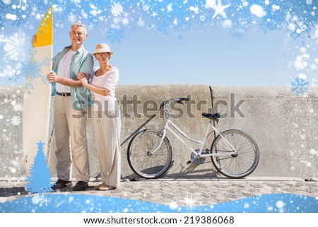 Happy senior couple posing with surfboard against snow