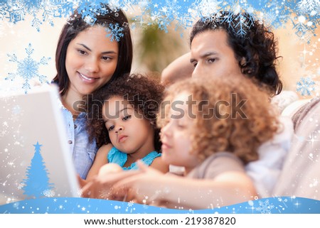 Composite image of happy family using laptop together against snow