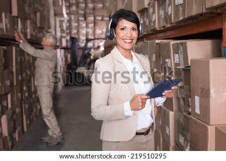 Pretty warehouse manager using tablet pc in a large warehouse