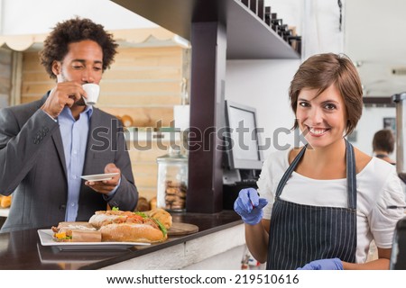 Happy server preparing food at counter at the coffee shop