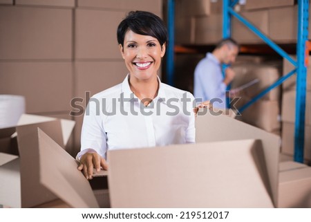 Pretty warehouse manager looking in box in a large warehouse