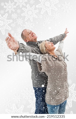 Composite image of Happy mature couple in winter clothes with snowflakes on silver