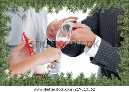 Close up of two colleague drinking champagne to celebrate christmas against green fir branches