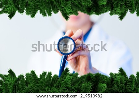 Doctor holding out stethescope with focus on object against fir tree branches forming frame