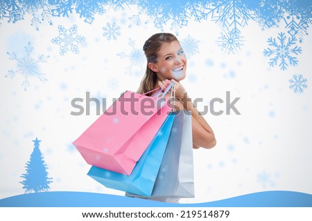 Back view of a cheerful woman holding shopping bags against snow flake frame in blue