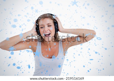 Happy woman singing while listening to music against snow falling