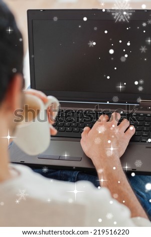 Over shoulder view of young man using his laptop against snow falling