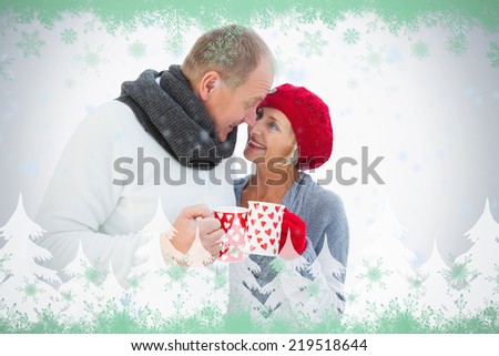 Happy mature couple in winter clothes holding mugs against green snowflake design