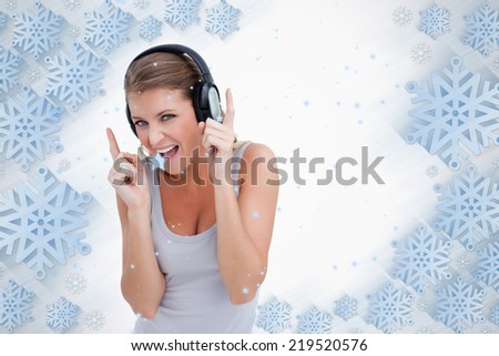 Cheerful woman dancing while listening to music against snowflake frame