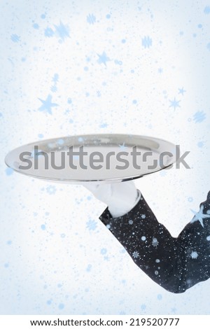 White gloved hand holding a silver tray against snow falling