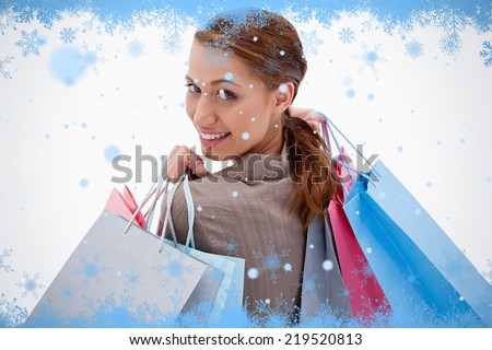 Back view of smiling woman with shopping bags against snow flake frame in blue
