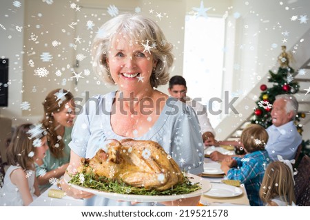 Composite image of Happy grandmother with Christmas meal against snow
