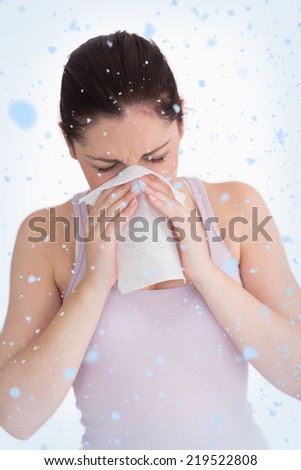 Composite image of woman blowing her nose against snow falling