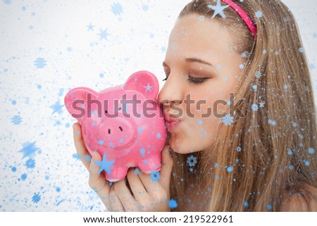 Close up of a young woman kissing a piggybank against snow falling