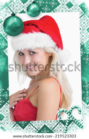 Composite image of a Happy young woman wearing santa hat against christmas frame