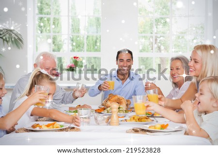 Composite image of Family toasting at thanksgiving against snow falling