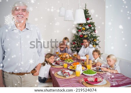 Composite image of Smiling grandfather standing at the dinner table against snow falling