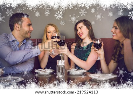 Friends clinking red wine glasses at a bar against fir tree forest and snowflakes