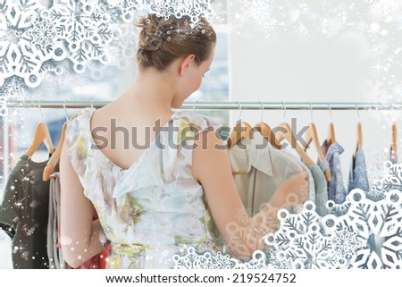 Female customer selecting clothes at clothing rack in store against snow