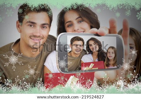 Hand holding smartphone showing photo against snow flake frame in green