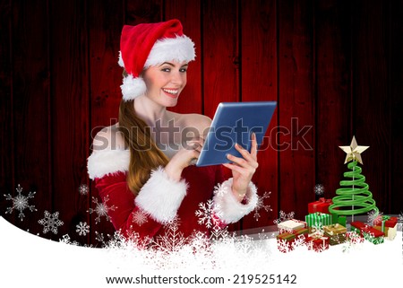 Pretty santa girl using tablet pc against christmas themed frame with tree