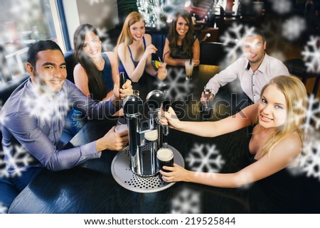 Young friends sitting together and pulling pints in a restaurant against snowflakes