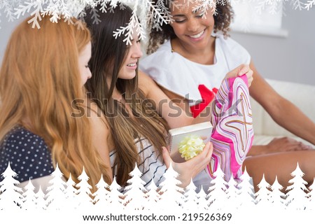 Cheerful young women surprising friend with a gift against fir tree forest and snowflakes