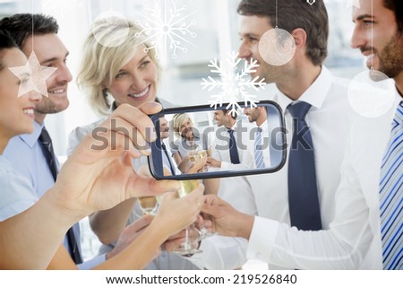 Hand holding smartphone showing photo against hanging decorations