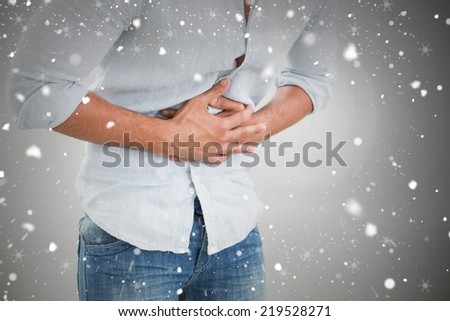 Mid section of man suffering from stomach pain against snow falling