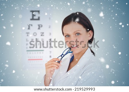Composite image of kind female optician with an eye test against snow falling