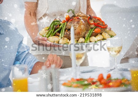 Woman bringing a roast chicken in the dining room against snow