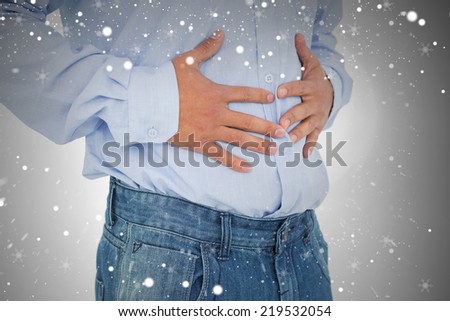Closeup mid section of a casual man with stomach pain against snow