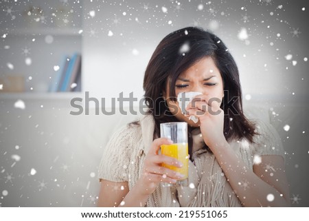 Composite image of sneezing woman drinking a glass of orange juice against snow falling