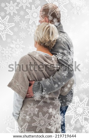 Composite image of Happy mature couple in winter clothes with snowflakes on silver