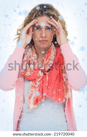 Composite image of Blonde woman touching her temples because of a headache with snow falling