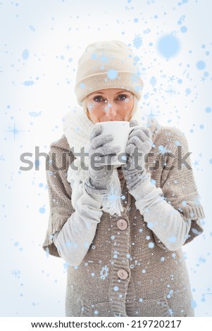 Composite image of Mature woman in winter clothes holding mug with snow falling