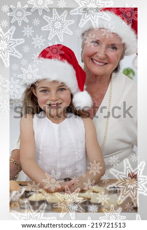 Smiling grandmother and little girl baking Christmas cakes against snowflakes on silver