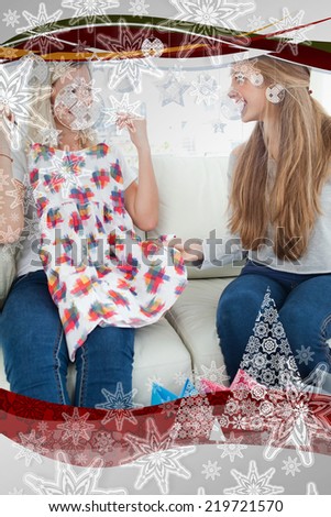 Composite image of Girls looking at each other as they try out new clothes with christmas frame