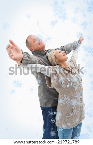 Composite image of Happy mature couple in winter clothes with snow falling