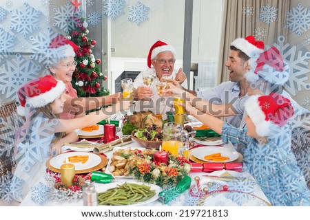 Family in santas hats toasting wine glasses at dining table against snowflake frame