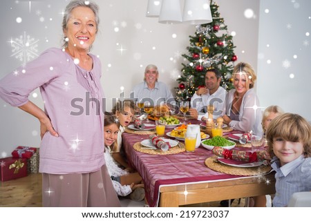 Composite image of Grandmother standing beside dinner table against snow falling